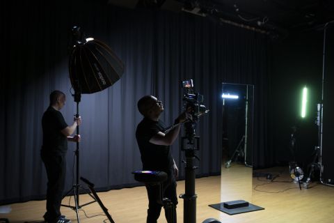 Henkilöt pystyttävät valon ja kameran studioon.