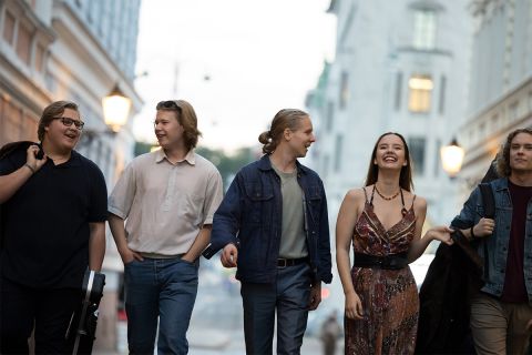 Work in Finlandin ja Business Finlandin brändikuva, jossa viisi henkilöä kävelevät ulkona muutaman soitin mukanaan.