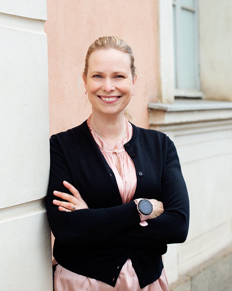 Henkilö nojaa rakennuksen ulkoseinään.