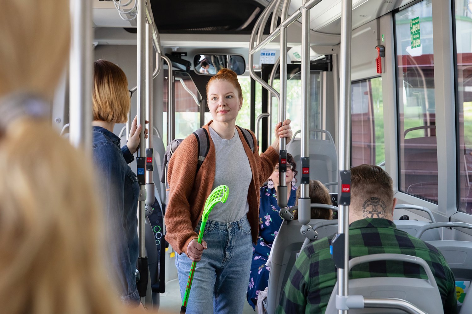 Henkilö salibandymailan kanssa bussissa.