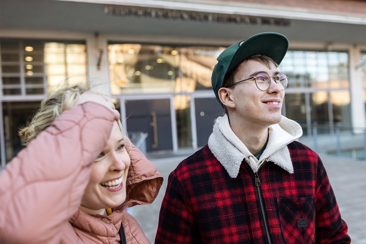 Kaksi henkilöä ulkona, molemmat hymyilevät.
