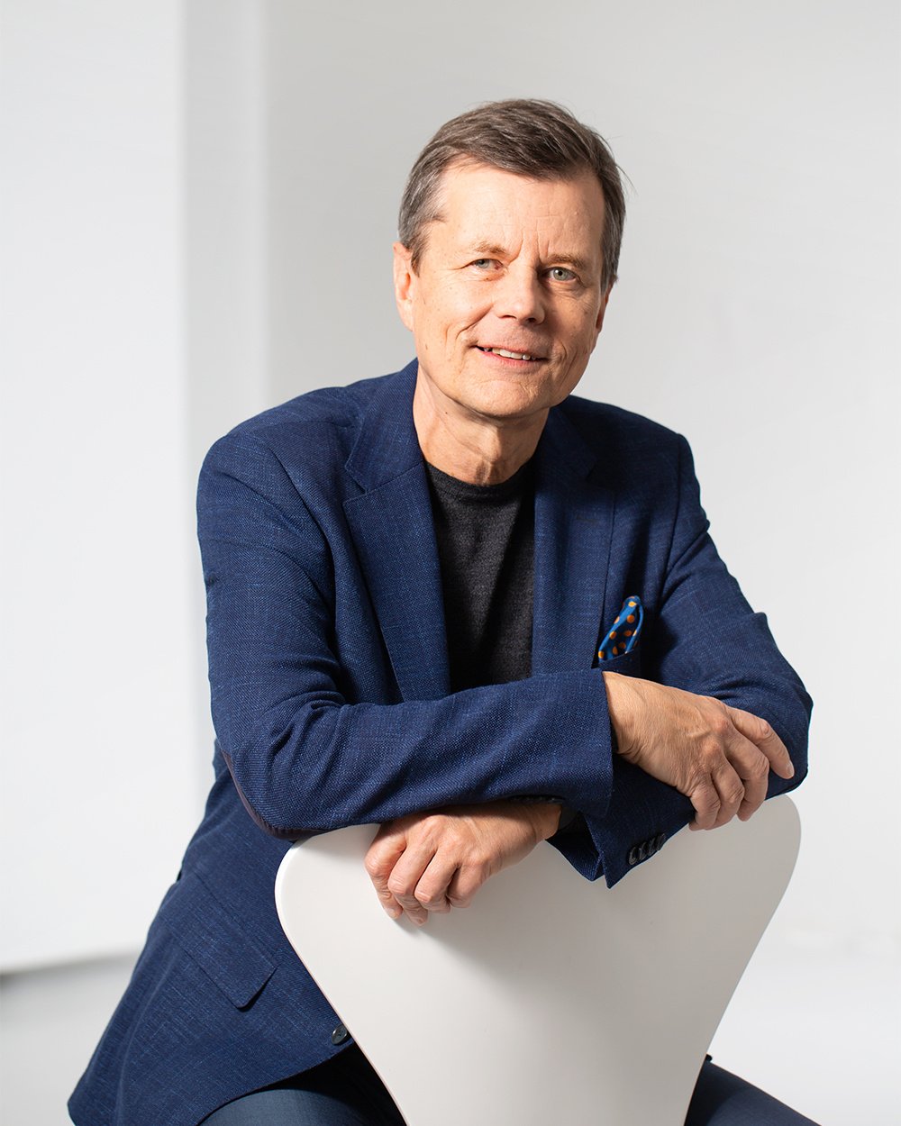Henkilö istuu tuolilla ja hymyilee.