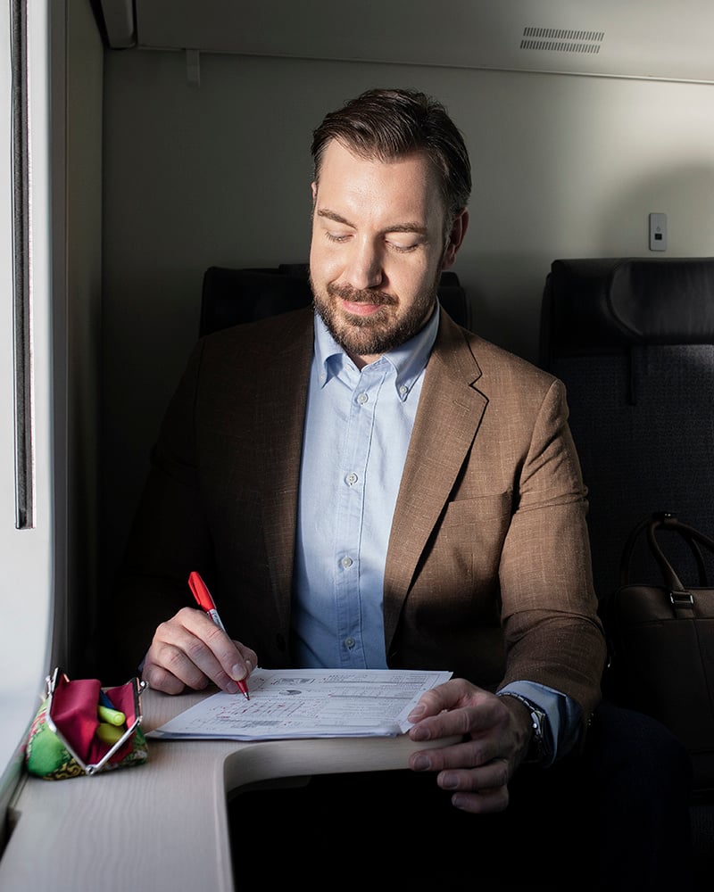 Henkilö kirjoittaa paperille junassa.
