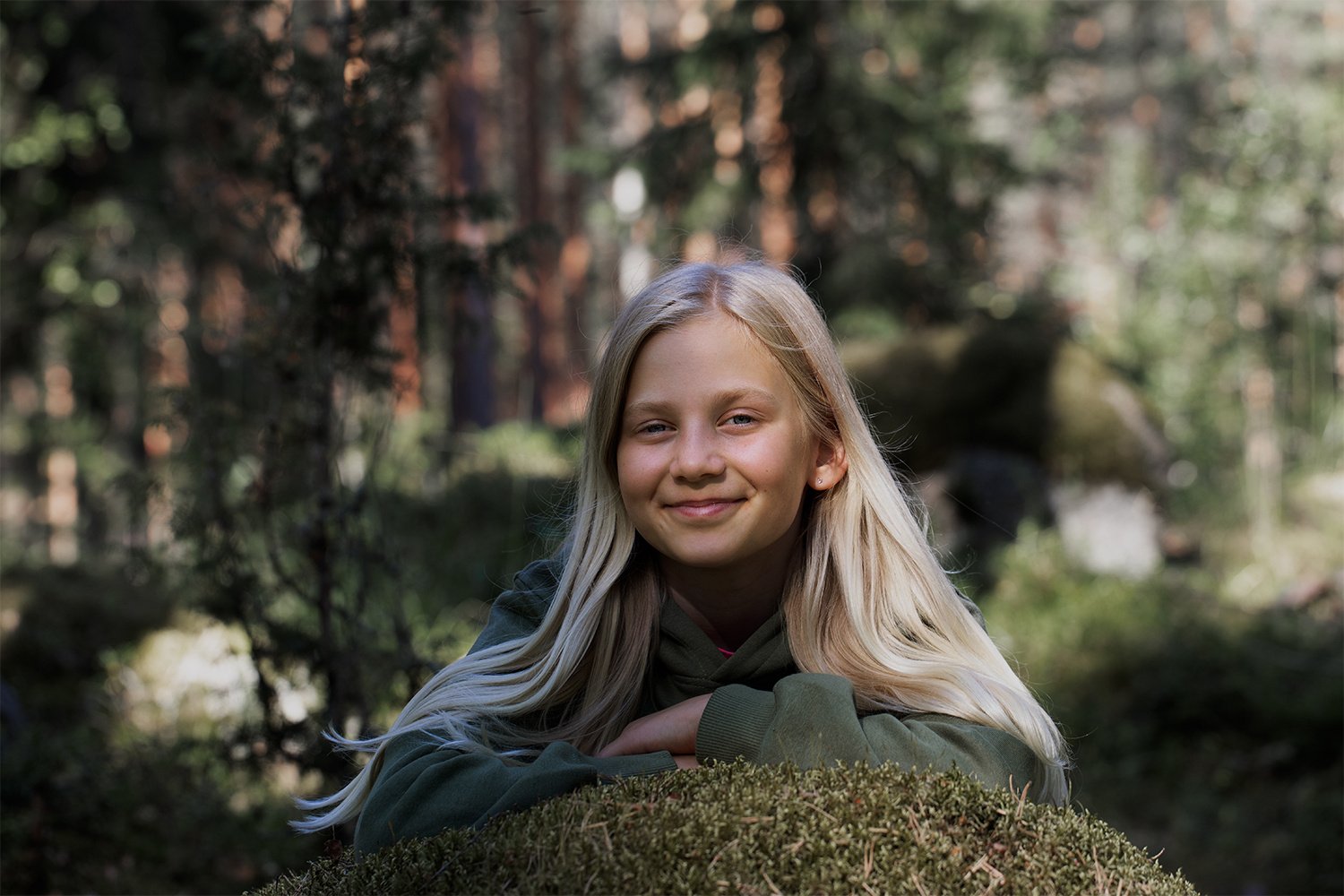 Nuori hymyilee metsässä.