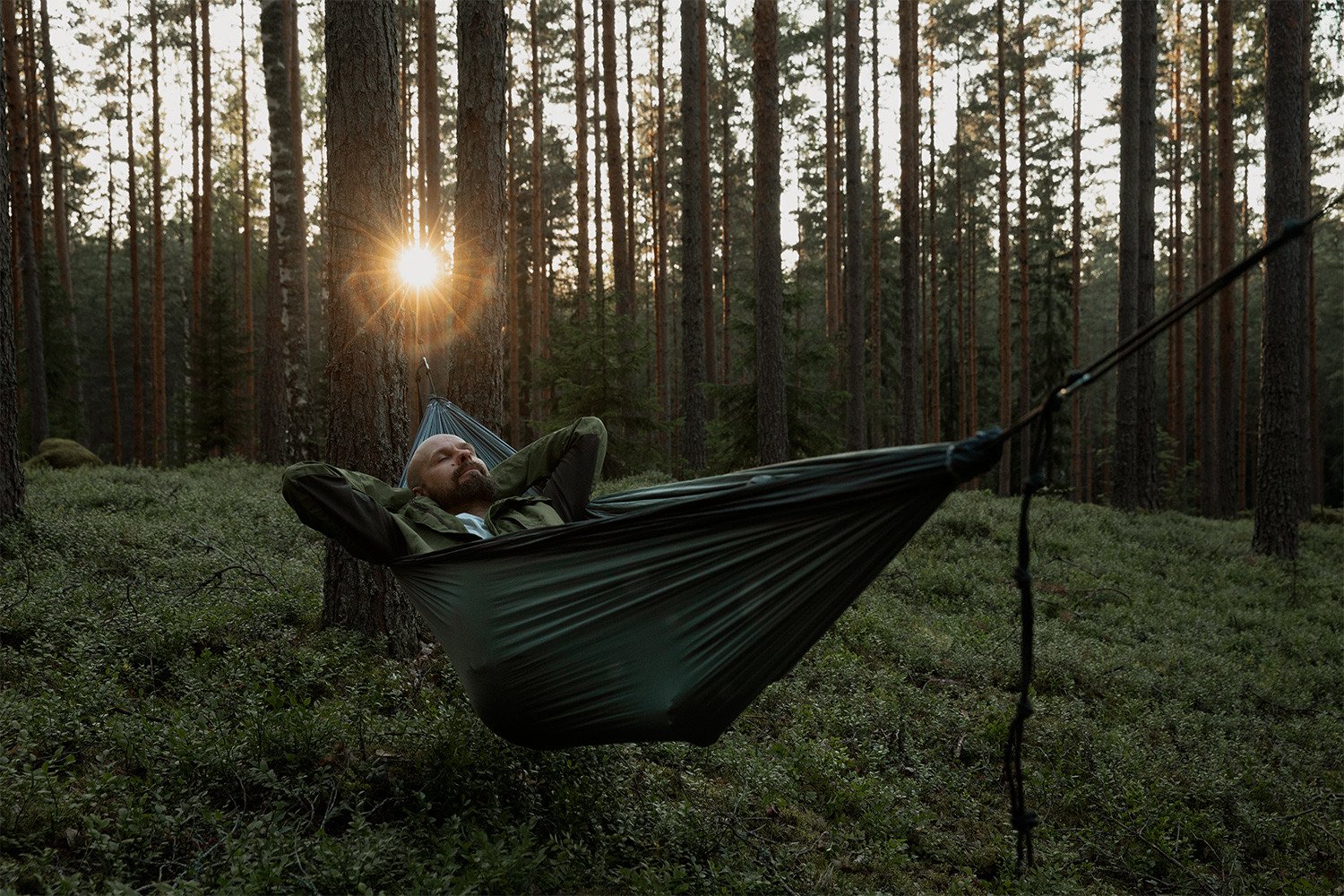 Henkilö makaa riippumatossa metsässä.